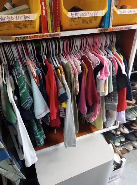 A rack of children's clothing on hangers.