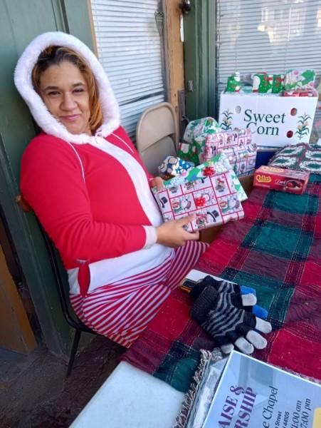 Tia handing out wrapped holiday gifts during a Christmas giveaway.